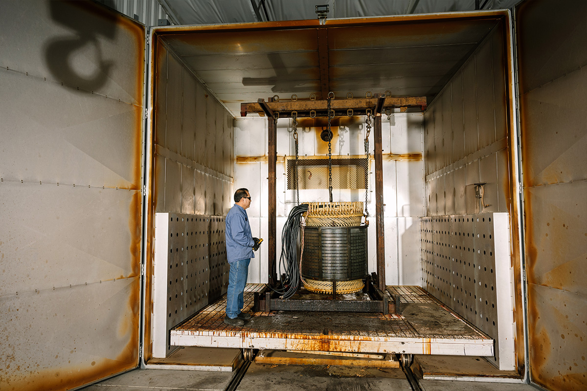 An H&N Electric technician inside a bake and burn oven with a component of a generator