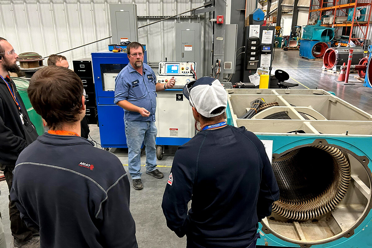 Several people watch as an H&N Electric technician teaches them as part of their wind turbine generator and motor 101 class in their fully-equipped repair facility