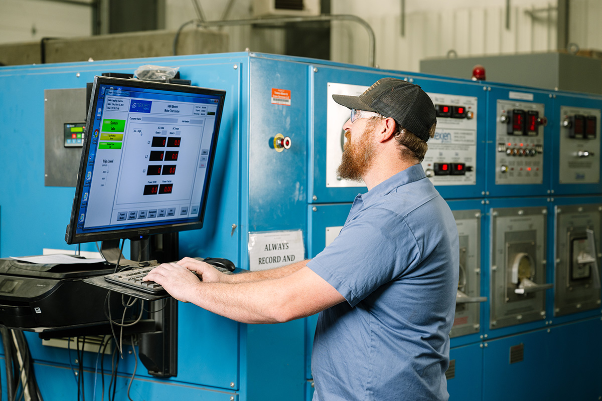 H&N technician working at a computer as a part of a preventative maintenance machine at the fully-equipped H&N Electric facility.